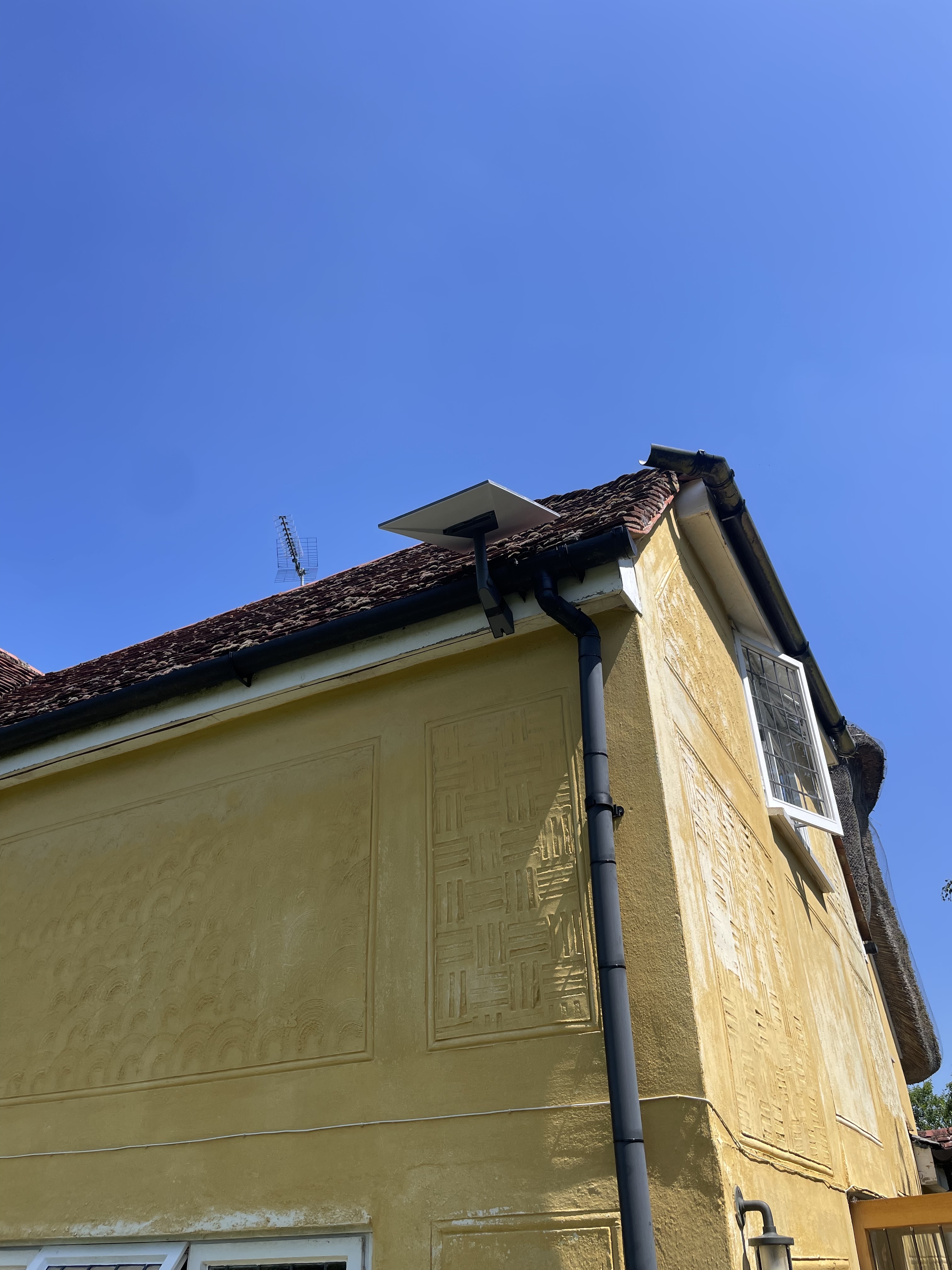 Starlink dish mounted above the gutter line on a rendered house