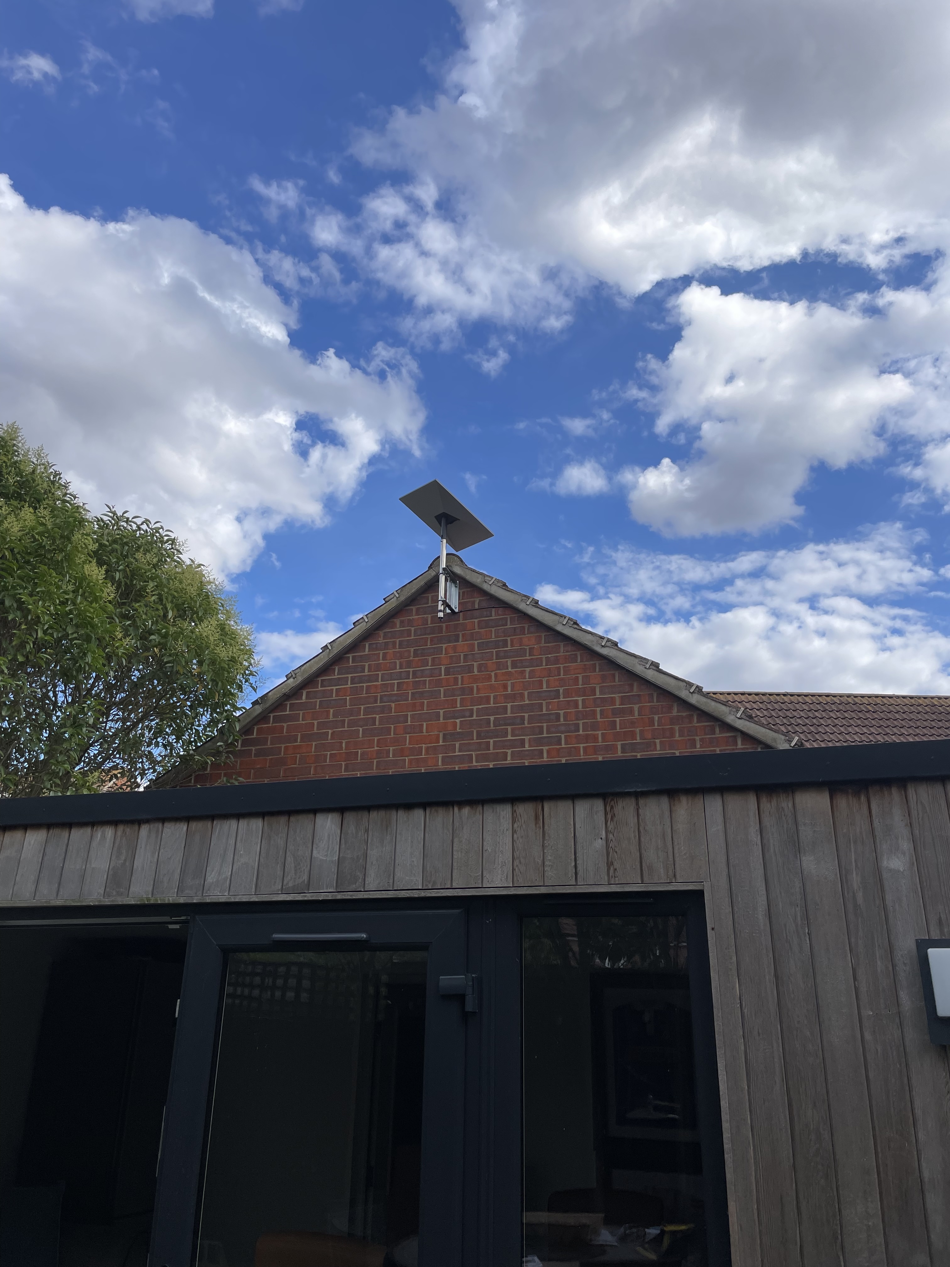 Starlink dish mounted above a brick gable and garden room
