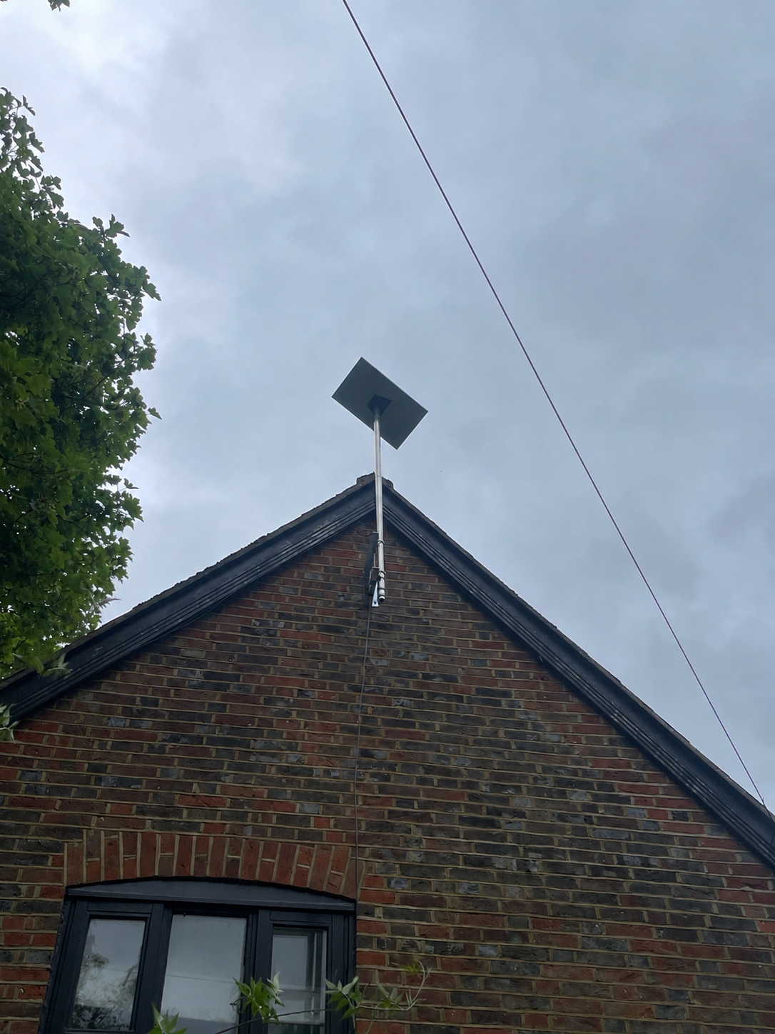 Tall Starlink gable mast installation on a brick property